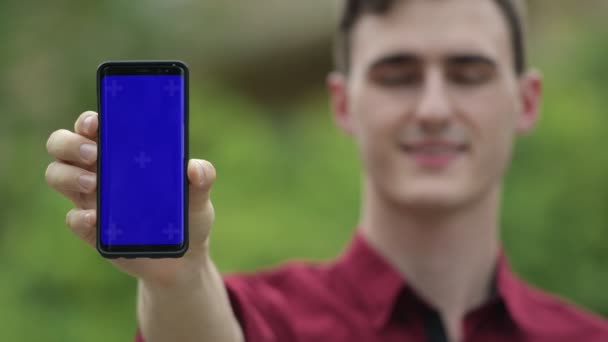 Joven hombre de negocios guapo mostrando el teléfono en las calles al aire libre — Vídeo de stock