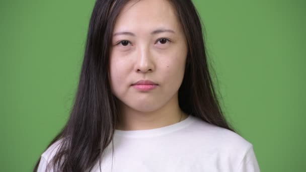 Jonge gelukkig Aziatische vrouw die lacht tegen groene achtergrond — Stockvideo