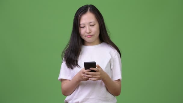 Young Asian woman thinking while using phone — Stock Video