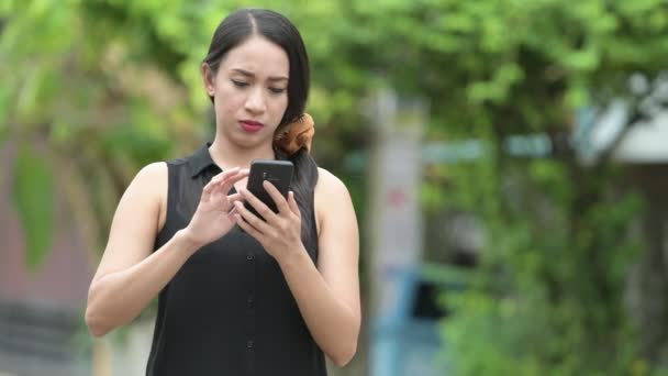 Giovane bella donna d'affari asiatica utilizzando il telefono per le strade all'aperto — Video Stock