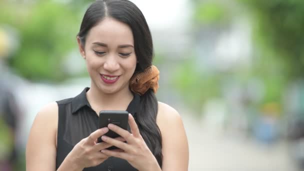 Giovane bella donna d'affari asiatica utilizzando il telefono per le strade all'aperto — Video Stock