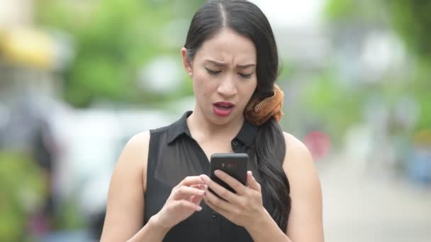 Unga vackra asiatiska affärskvinna med telefon på gatorna utomhus — Stockvideo