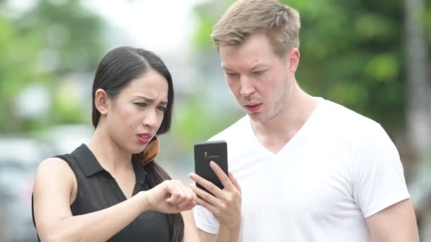 Mladý multi-etnický pár společně pomocí telefonu v ulicích venku — Stock video
