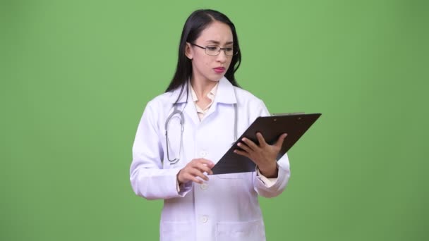 Молодая красивая азиатка-врач думает, держа планшет — стоковое видео