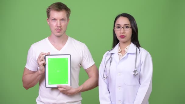 Fiatal ázsiai nő orvos, a fiatalember beteg találat digitális tabletta — Stock videók