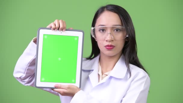 Молода жінка красива Азіатська лікар носити захисні окуляри і показуючи цифровий планшетний — стокове відео