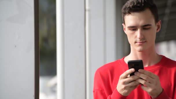 Młody przystojny mężczyzna szczęśliwy przy użyciu telefonu — Wideo stockowe