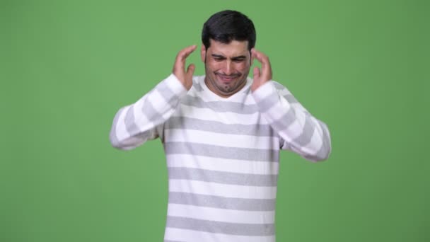 Junger gestresster persischer Mann deckt Ohren vor lauten Geräuschen ab — Stockvideo