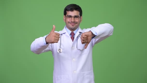 Young handsome Persian man doctor choosing between thumbs up and thumbs down — Stock Video