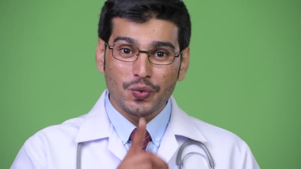 Young handsome Persian man doctor with finger on lips — Stock Video