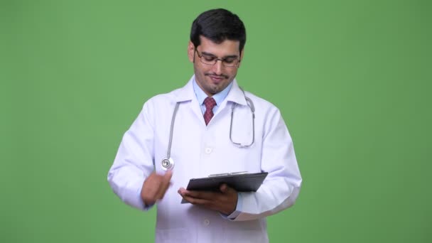 Joven guapo hombre persa doctor leyendo en portapapeles — Vídeo de stock