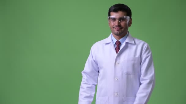 何かを示す保護メガネを身に着けている若いハンサムなペルシャ男医師 — ストック動画