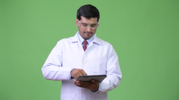 Joven guapo médico persa con gafas protectoras usando tableta digital — Vídeos de Stock