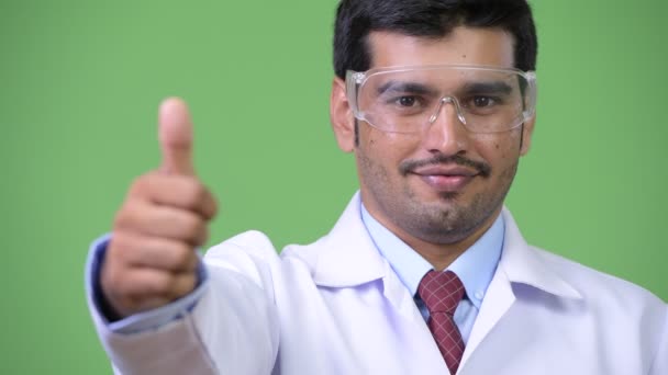 Joven guapo médico persa con gafas protectoras dando pulgares hacia arriba — Vídeos de Stock