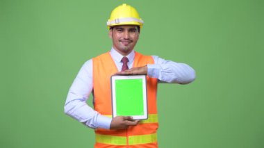 Genç yakışıklı Farsça adam inşaat işçisi gösteren dijital tablet