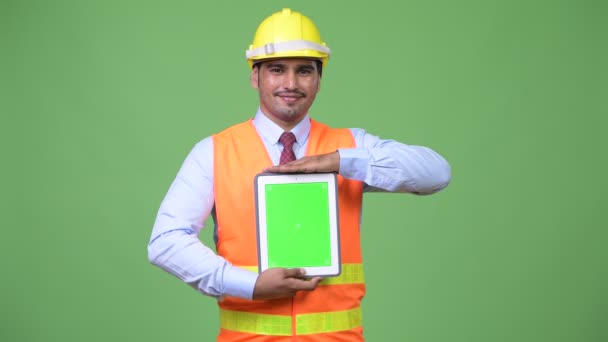 Joven hombre persa guapo trabajador de la construcción mostrando tableta digital — Vídeos de Stock