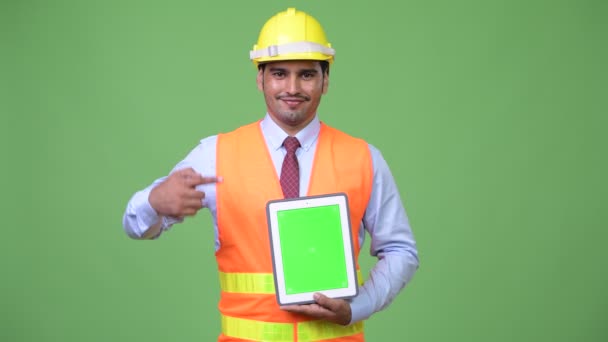 Jovem bonito homem persa trabalhador da construção mostrando tablet digital — Vídeo de Stock