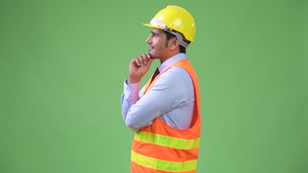 Profile view of young handsome Persian man construction worker thinking — Stock Video