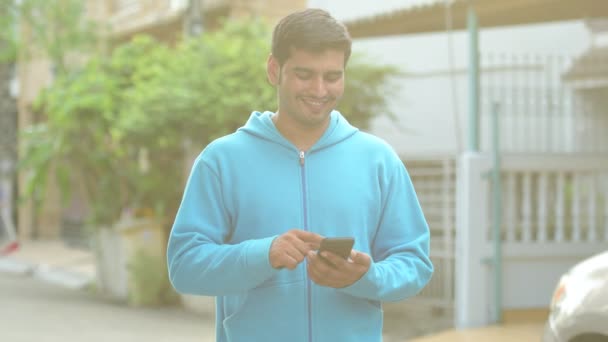 Ευτυχισμένος Περσικά νεαρός χρησιμοποιώντας τηλέφωνο σε εξωτερικούς χώρους — Αρχείο Βίντεο