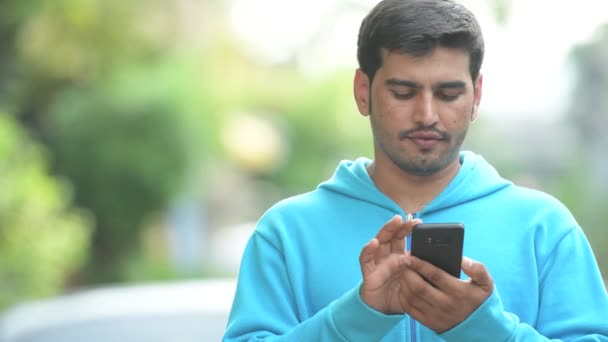 Молодой счастливый перс пользуется телефоном на улице — стоковое видео
