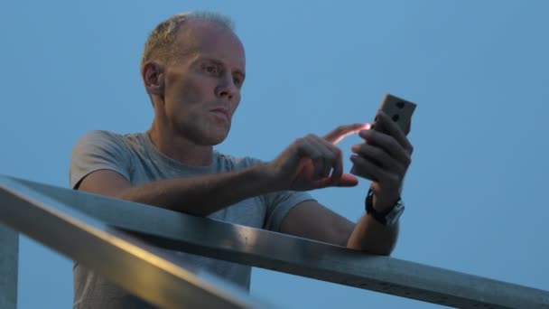 Hombre escandinavo maduro usando el teléfono contra la vista de la ciudad — Vídeo de stock