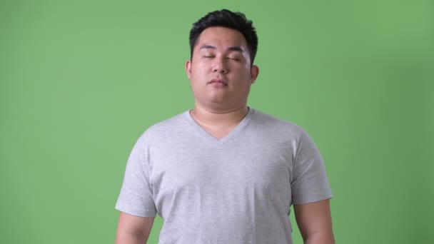 Young handsome overweight Asian man against green background — Stock Video