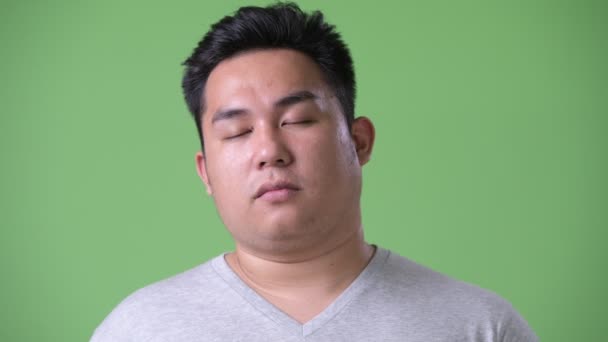 若いハンサムな太りすぎの緑の背景のクロマキーに対してアジア人のスタジオ撮影 — ストック動画