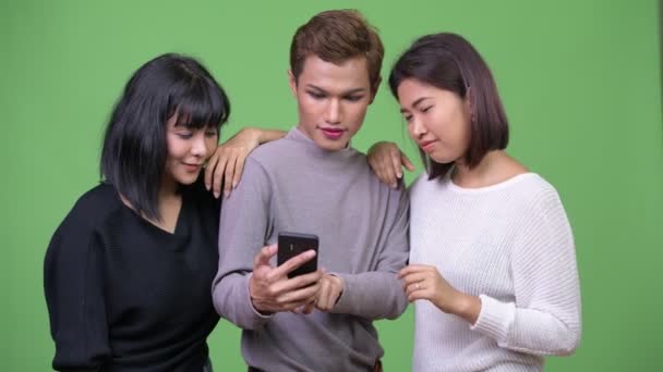 一緒に携帯電話を使用して 3 つの幸せなアジアの友人 — ストック動画