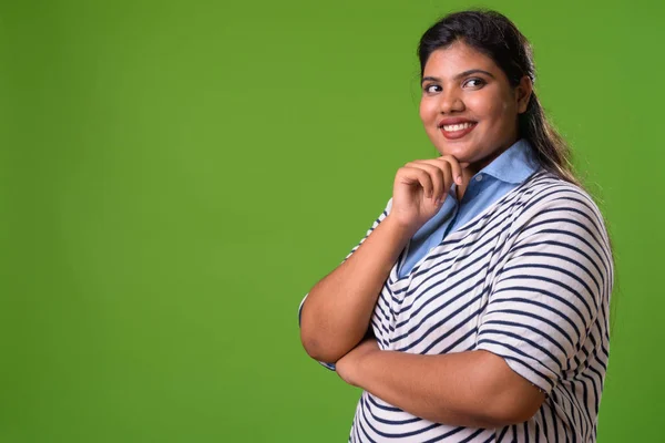 Молодая толстая красивая индийская предпринимательница на зеленом фоне — стоковое фото