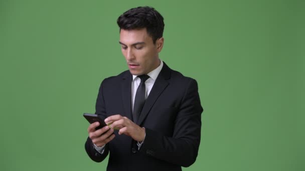 Young handsome Hispanic businessman against green background — Stock Video