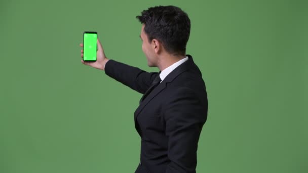 Young handsome Hispanic businessman against green background — Stock Video