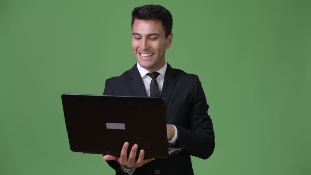 Jonge knappe Hispanic zakenman tegen groene achtergrond — Stockvideo