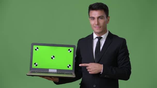 Young handsome Hispanic businessman against green background — Stock Video