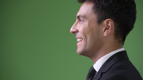 Young handsome Hispanic businessman against green background — Stock Video