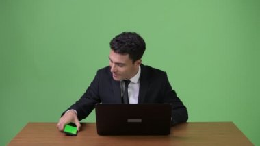 Genç yakışıklı İspanyol işadamı yeşil bir arka plana dayanır