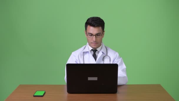 Молодой красивый латиноамериканец врач на зеленом фоне — стоковое видео