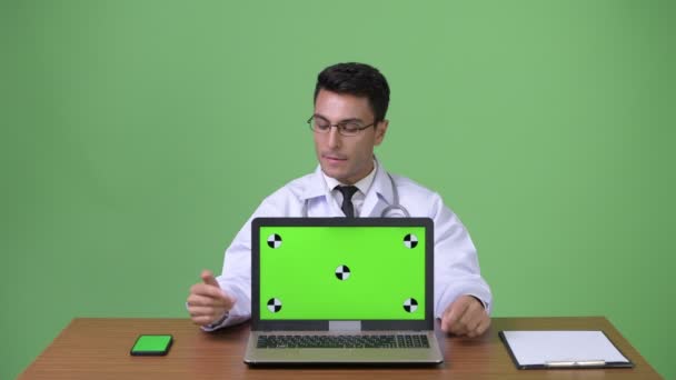 Genç yakışıklı İspanyol adam doktor yeşil bir arka plana dayanır — Stok video