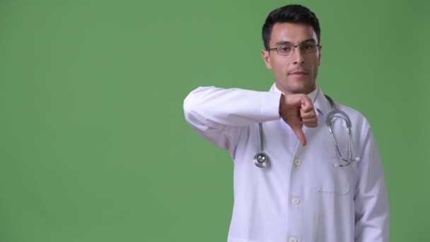 Jovem bonito homem hispânico médico contra fundo verde — Vídeo de Stock