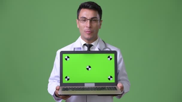 Young handsome Hispanic man doctor against green background — Stock Video