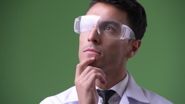 Young handsome Hispanic man doctor against green background — Stock Video