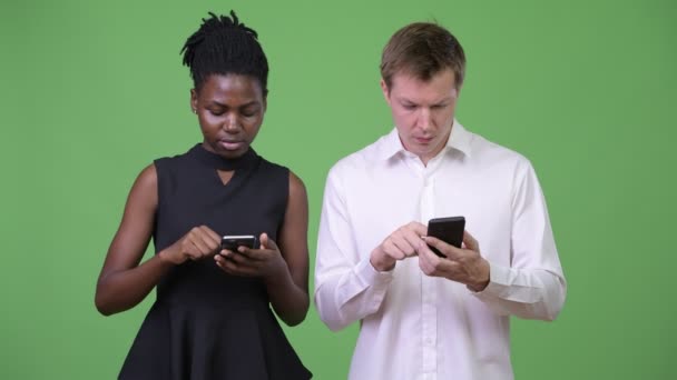 Two young multi-ethnic business couple using phone together — Stock Video