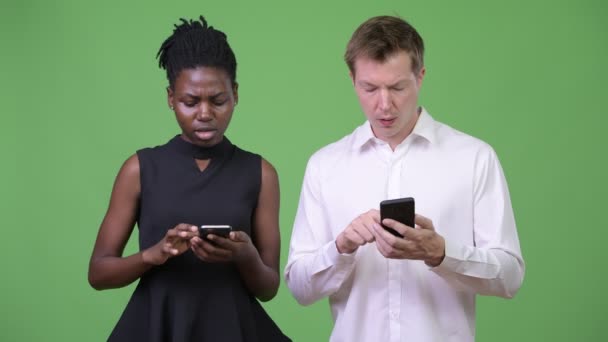 Två unga multietniska business par använda telefonen tillsammans — Stockvideo