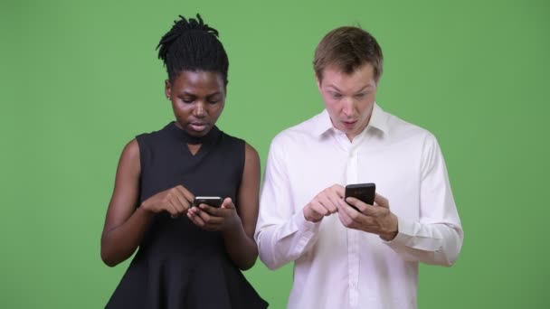 Two young multi-ethnic business couple using phone together — Stock Video