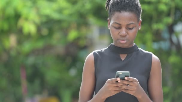 Young beautiful African businesswoman using phone outdoors — Stock Video