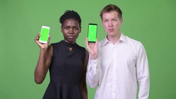 Dwóch młodych firm wieloetnicznego para wyświetlone telefonu razem — Wideo stockowe