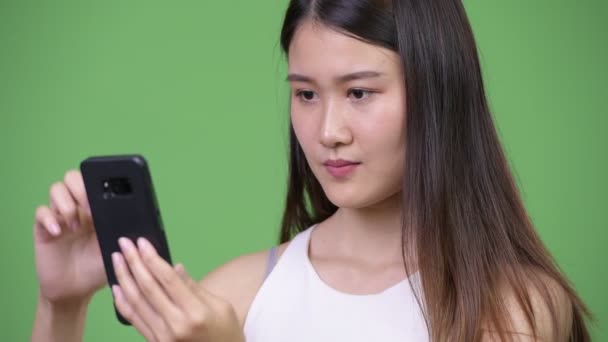 Νεαρή όμορφη Ασιάτισσα επιχειρηματίας που χρησιμοποιεί τηλέφωνο — Αρχείο Βίντεο