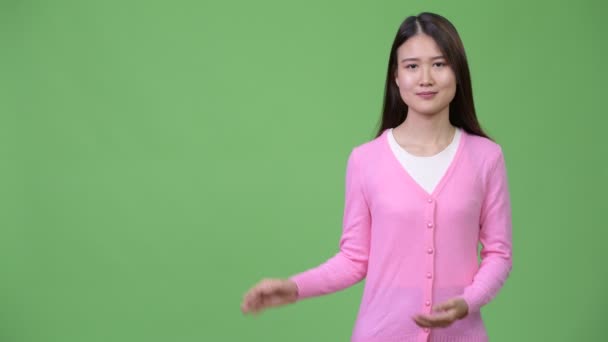 Ung vacker asiatisk kvinna visar något — Stockvideo