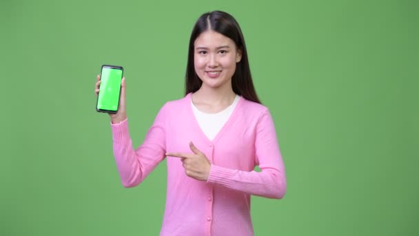 Joven hermosa mujer asiática mostrando teléfono — Vídeo de stock