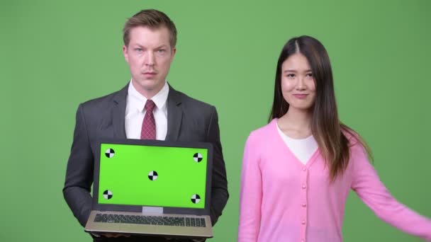 Giovane donna asiatica e giovane uomo d'affari che mostra computer portatile insieme — Video Stock