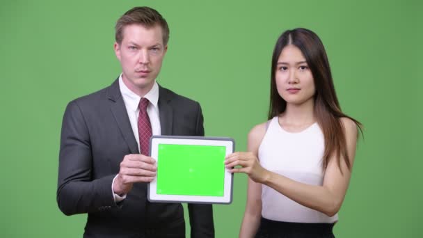 Pareja de negocios multiétnicos mostrando tableta digital juntos — Vídeos de Stock